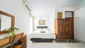 Una camera da letto con un letto, un armadio in legno, uno specchio e una pianta.