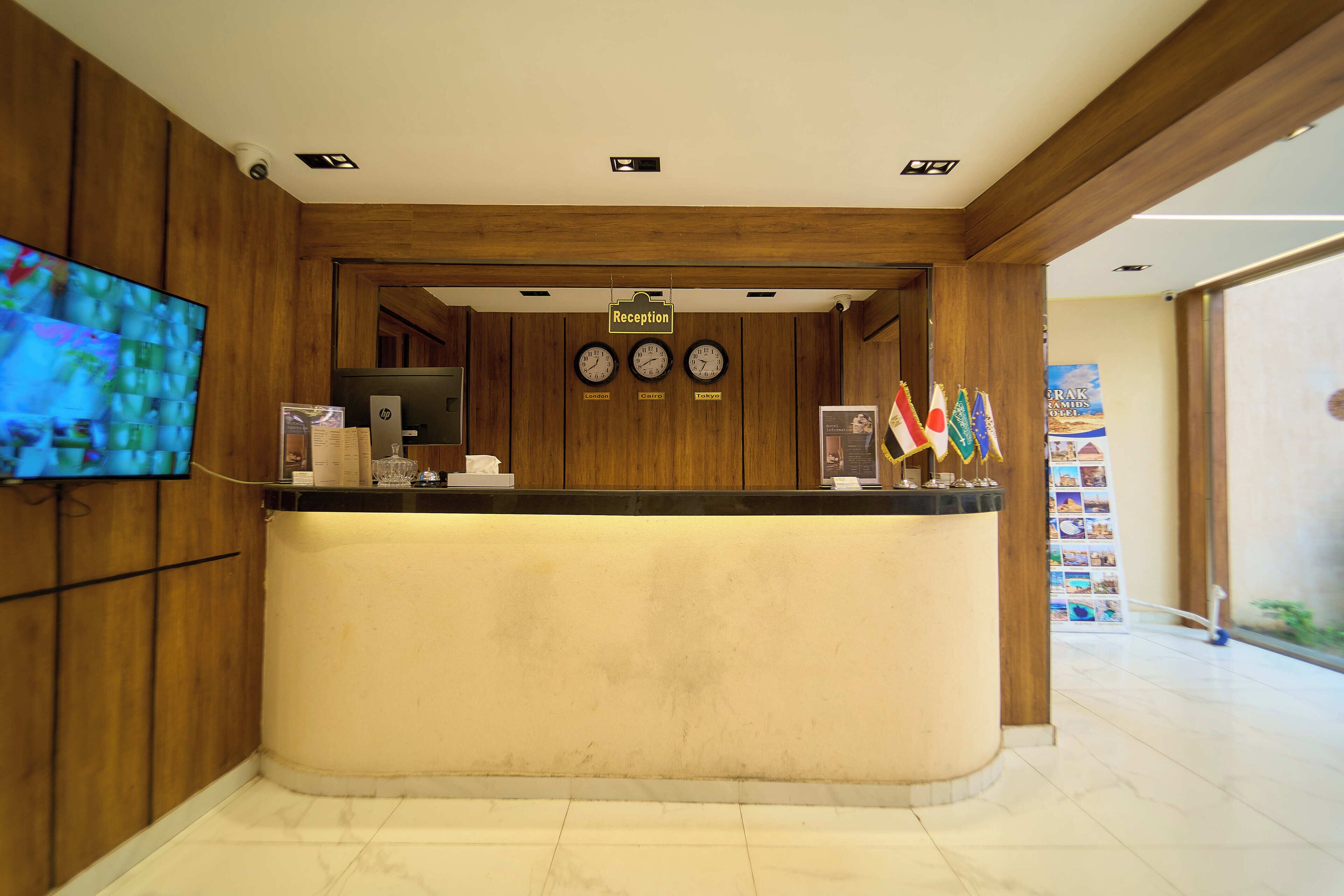 A reception desk with a clock, a television, and flags.