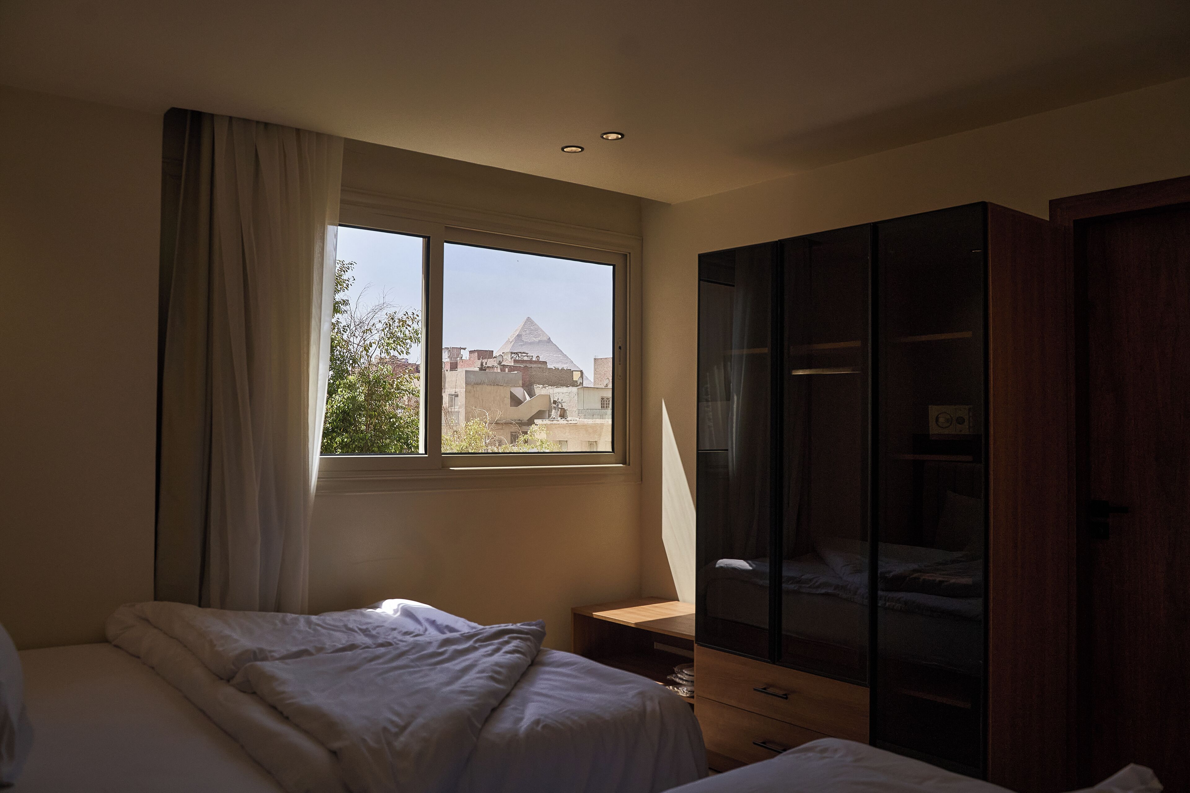 Ein Schlafzimmer mit großem Fenster, einem Bett, einem Nachttisch und einem Kleiderschrank.