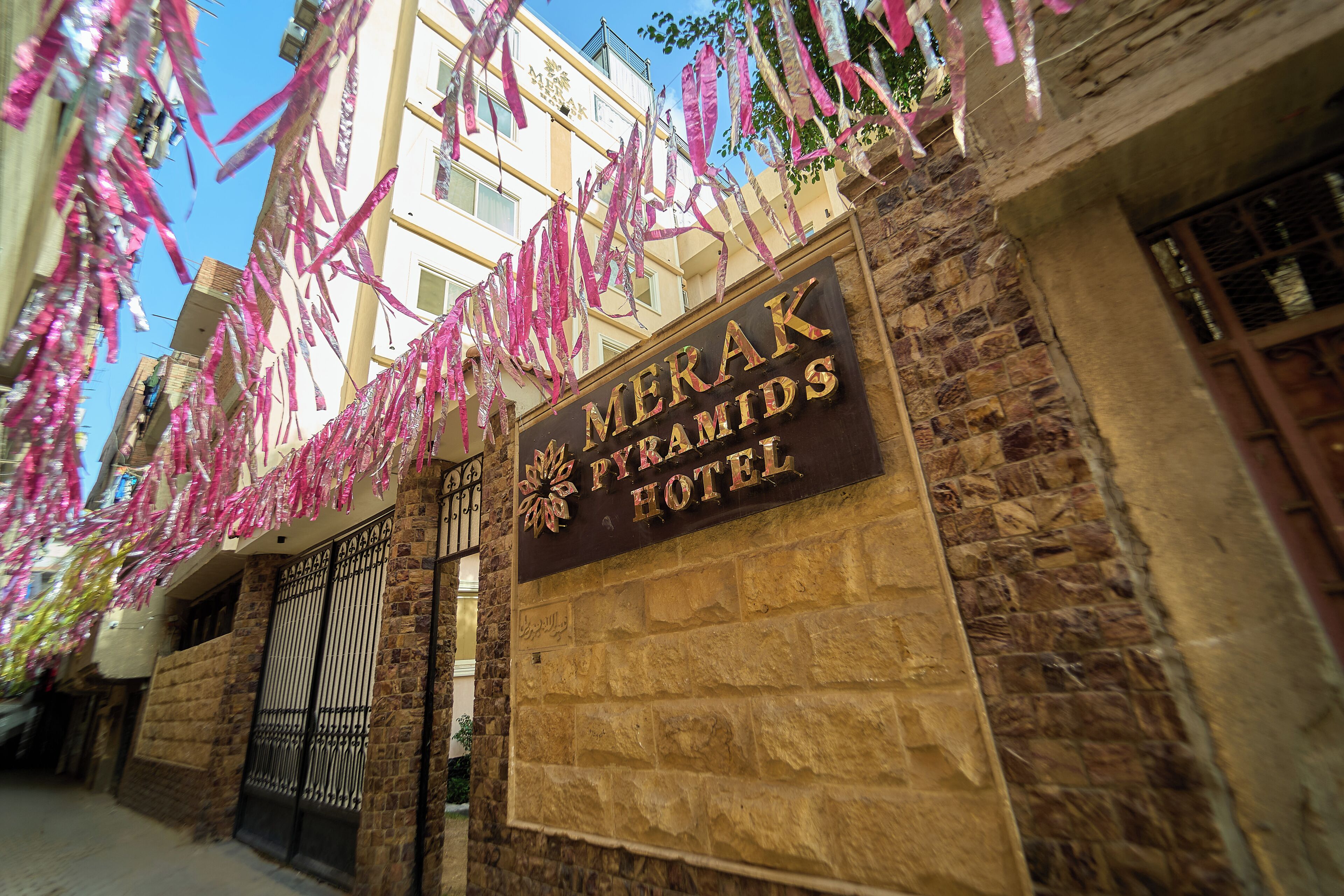A hotel entrance with a stone facade, a metal gate, and a sign above the gate.