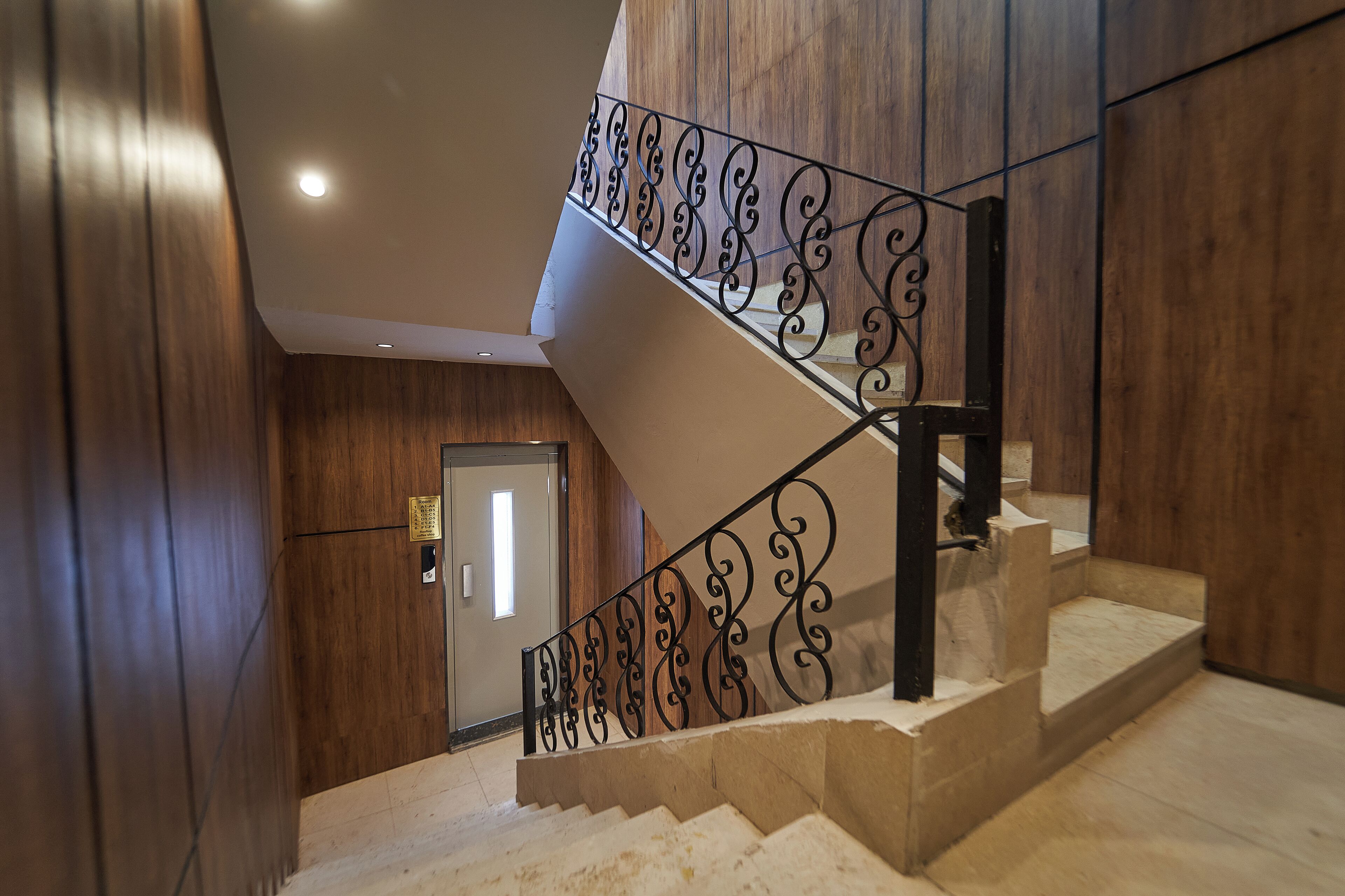 A staircase with ornate black railings and a wooden wall.