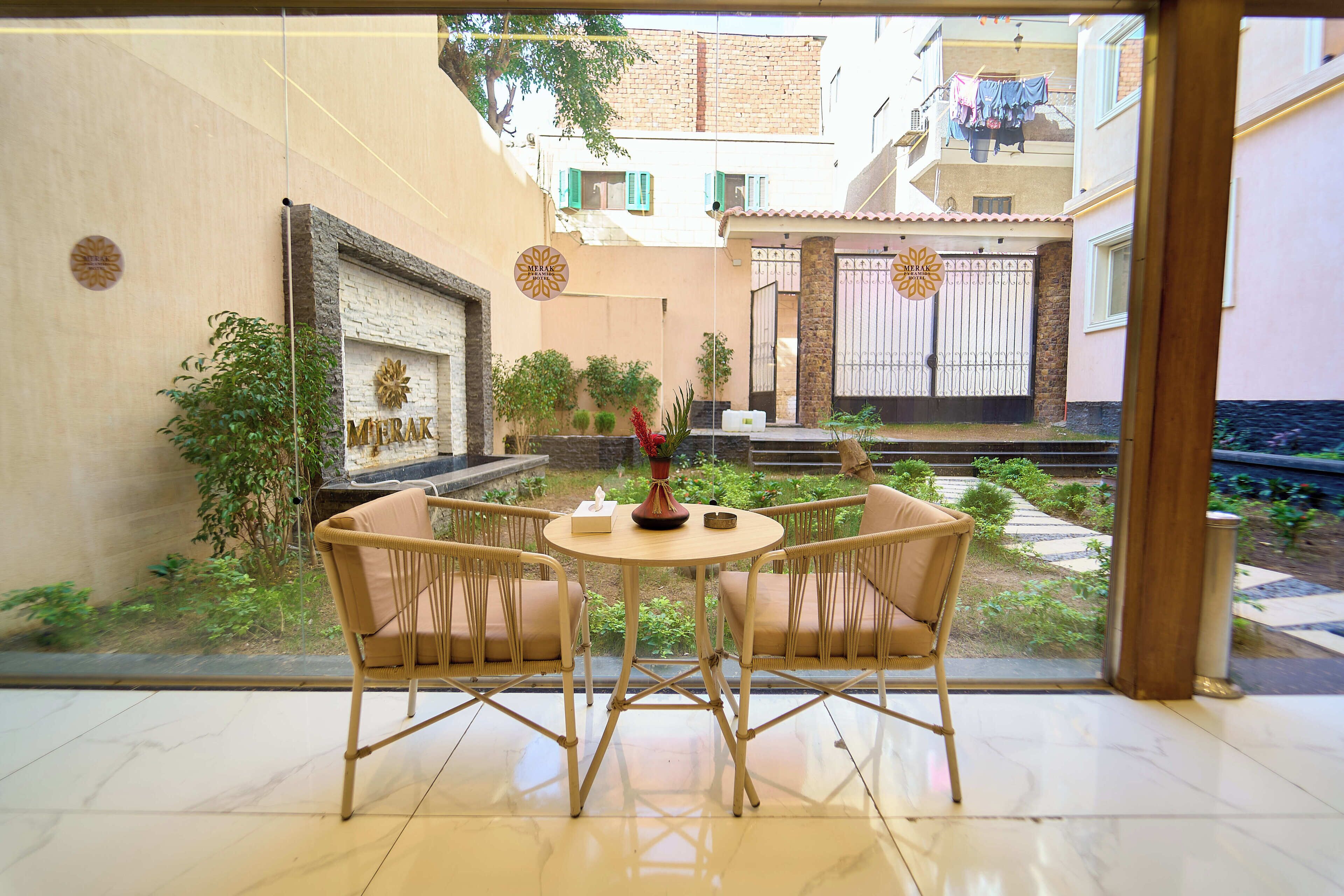 A room with a view of a courtyard, a small round table with chairs, and a wall-mounted sign.