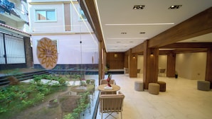A modern hotel lobby with a glass wall, a reception desk, and a seating area with chairs and ottomans. - Merak Pyramids View Hotel (Giza)