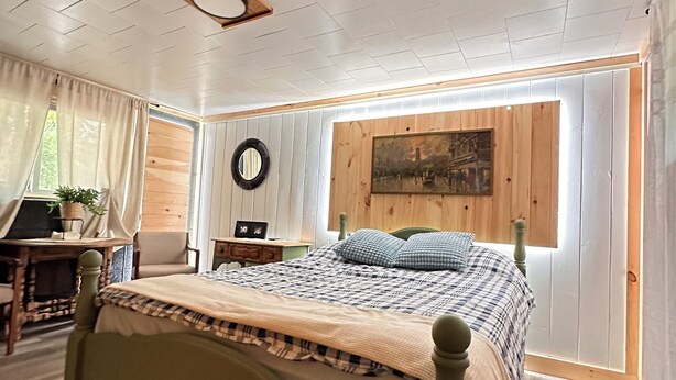 Een slaapkamer met een houten bed, een bureau en een raam met gordijnen.