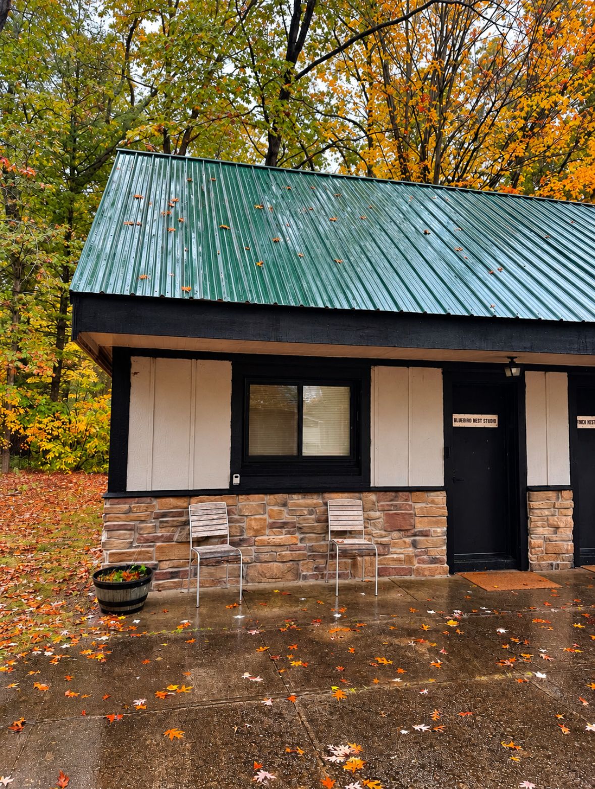 A building with a green roof, stone walls, and two doors labeled 'Bluebird Nest Studio.'