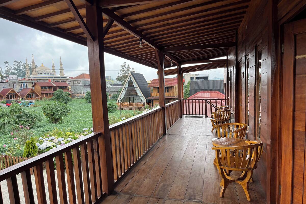 A wooden balcony with a view of a traditional building and a modern house.