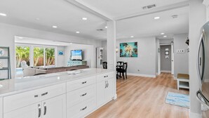 Una cocina moderna con armarios blancos, una isla grande y un comedor con mesa y sillas.