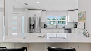Una cocina moderna con una isla grande, electrodomésticos de acero inoxidable y un ventanal con vistas a zonas verdes.