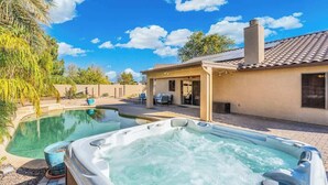 A backyard with a swimming pool and a hot tub, surrounded by a patio area with outdoor furniture.