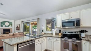 A modern kitchen with white cabinets, a built-in oven, a microwave, and a dishwasher.