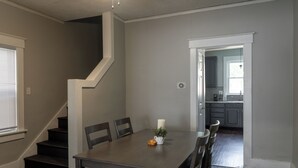 A dining area with a table, chairs, a candle, and a small plant. There is a staircase leading to another room.