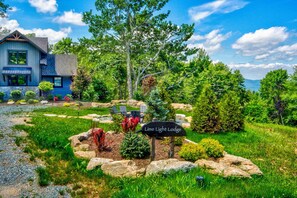 A lodge with a sign reading 'Lime Light Lodge,' surrounded by a garden with rocks, shrubs, and trees.