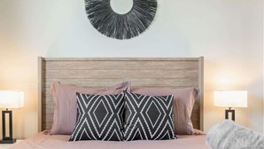 Une chambre à coucher avec une tête de lit en bois, deux lampes de chevet et un élément décoratif mural au-dessus du lit.