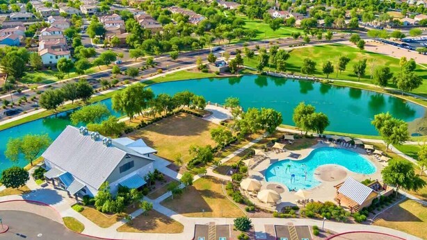 Vue aérienne d’un quartier résidentiel avec une grande piscine entourée de maisons, un club-house et un terrain de golf.