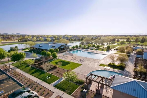 An aerial view of a resort with multiple swimming pools, a parking lot, and landscaped areas.