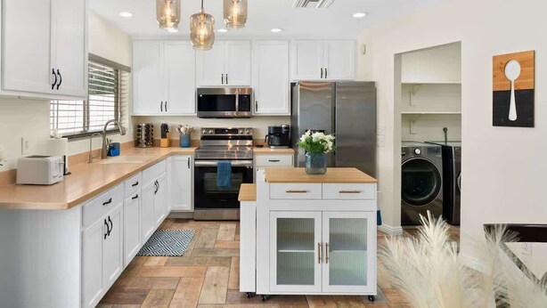 A modern kitchen with white cabinets, stainless steel appliances, and a central island. - *NEW* Western Desert Pool Oasis! Fire Pit & Grill! (Glendale)