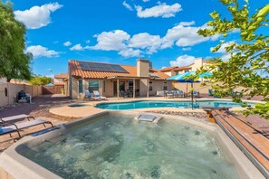 Un cortile con idromassaggio, piscina e patio coperto.