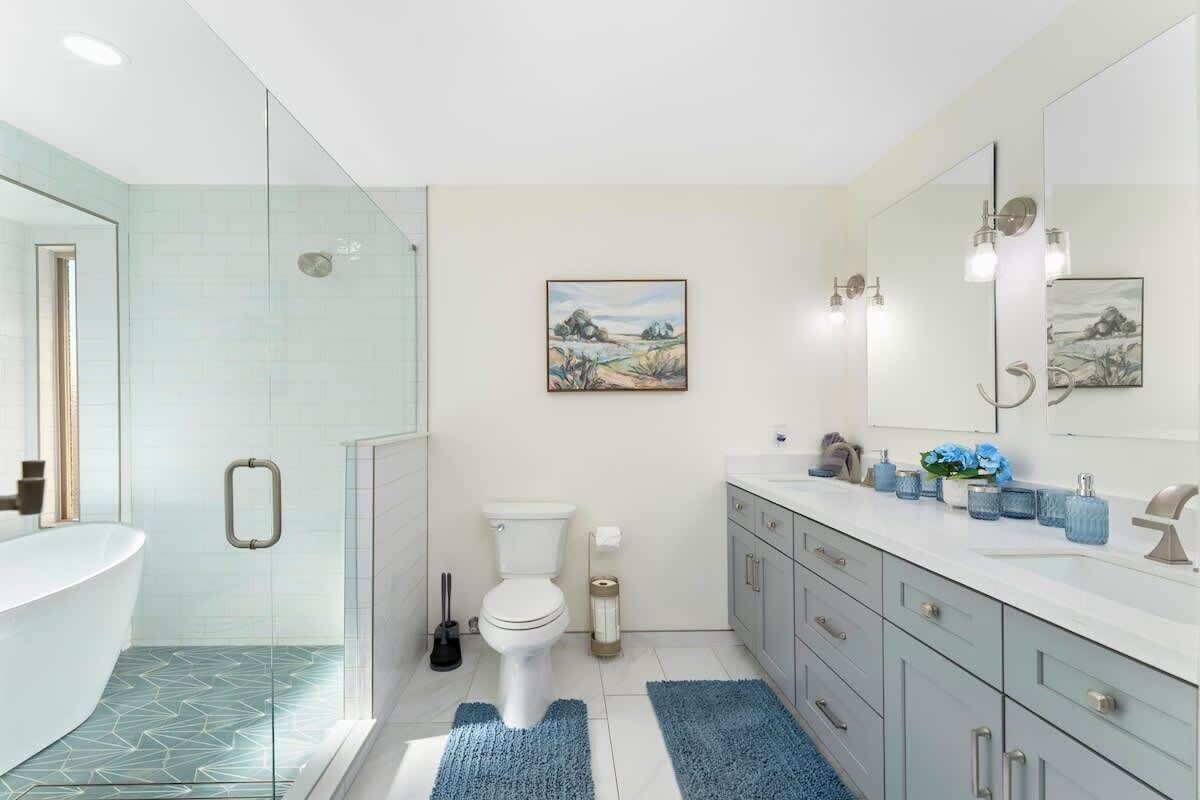 A modern bathroom with a glass shower enclosure, a white toilet, and a large mirror above the sink.