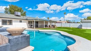 Ein Pool mit Whirlpool, eine überdachte Terrasse mit Gartenmöbeln und ein gepflegter Rasen.