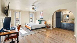 Een kleine hotelkamer met een bed, bureau en kitchenette.