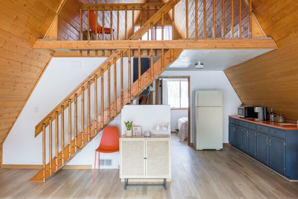 A spacious loft with a wooden staircase, a kitchenette, and a dining area.
