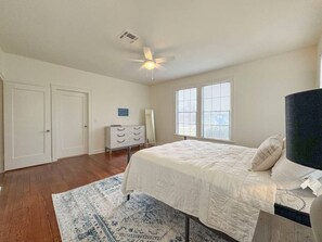 Ein Schlafzimmer mit einem Bett, einem Schminktisch, einem Deckenventilator und einem Fenster.