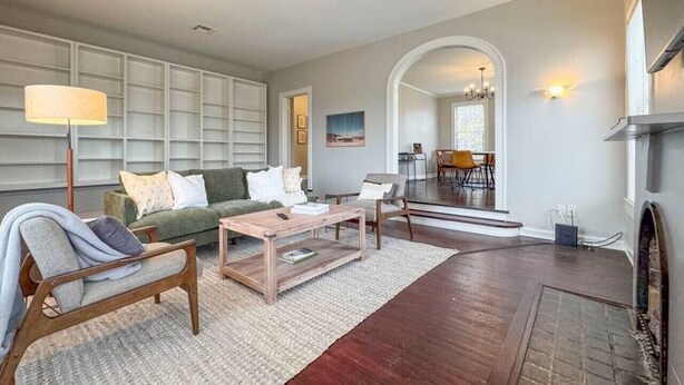 A spacious living room with a fireplace, a sofa, a coffee table, and a dining area visible through an archway.