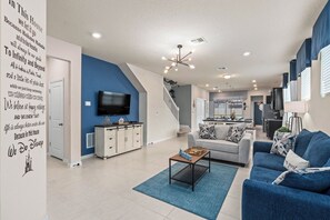 Un salon moderne avec un mur d’accent bleu, un téléviseur à écran plat, une table basse et un canapé.