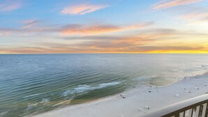 Una playa con vista despejada al océano y una puesta de sol al fondo.