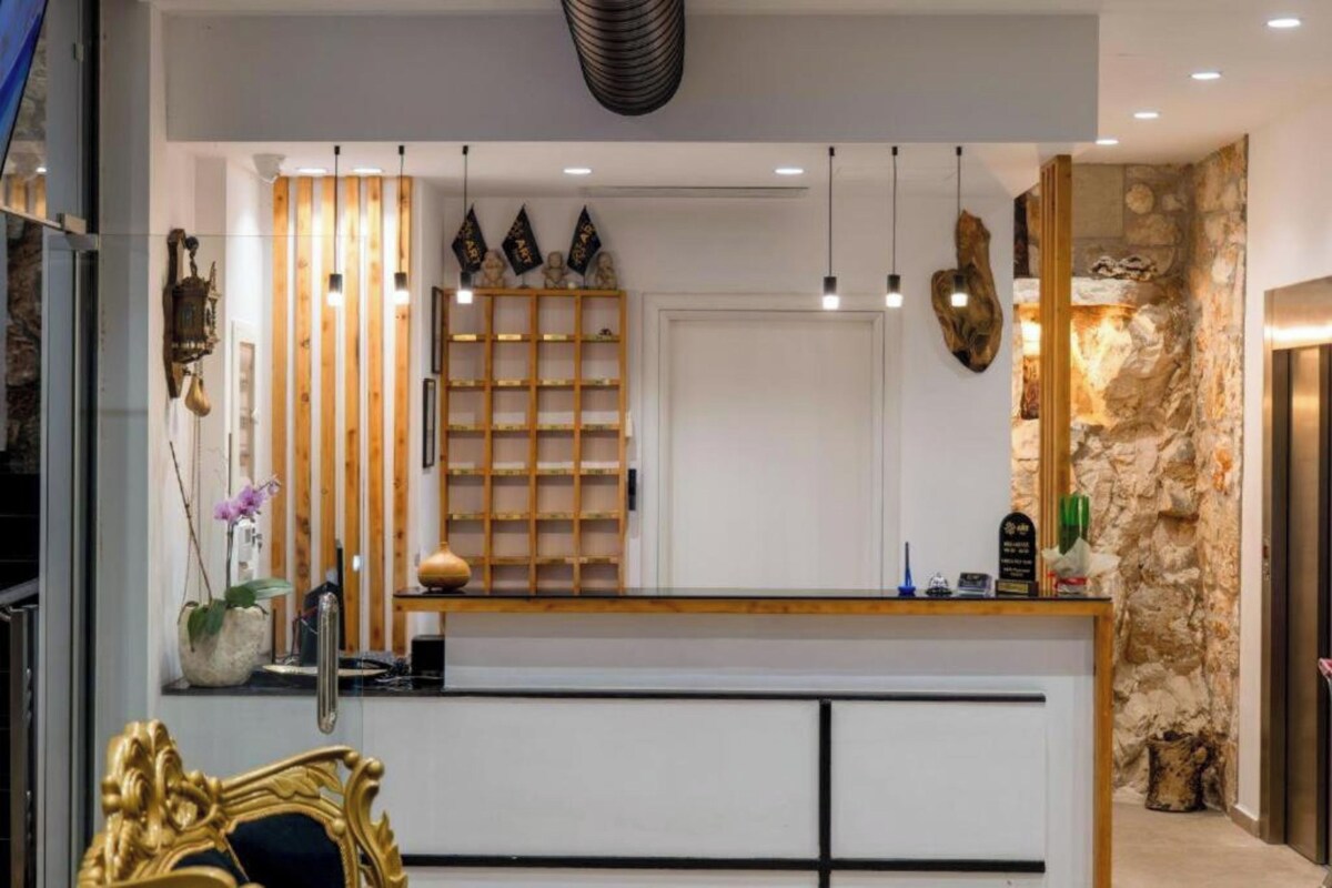 A reception area with a wooden counter, pendant lights, a stone wall, and a decorative shelf with items.