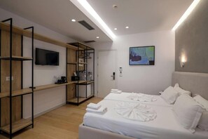 Una habitación de hotel moderna con una cama, televisor, armario y un cuadro en la pared.