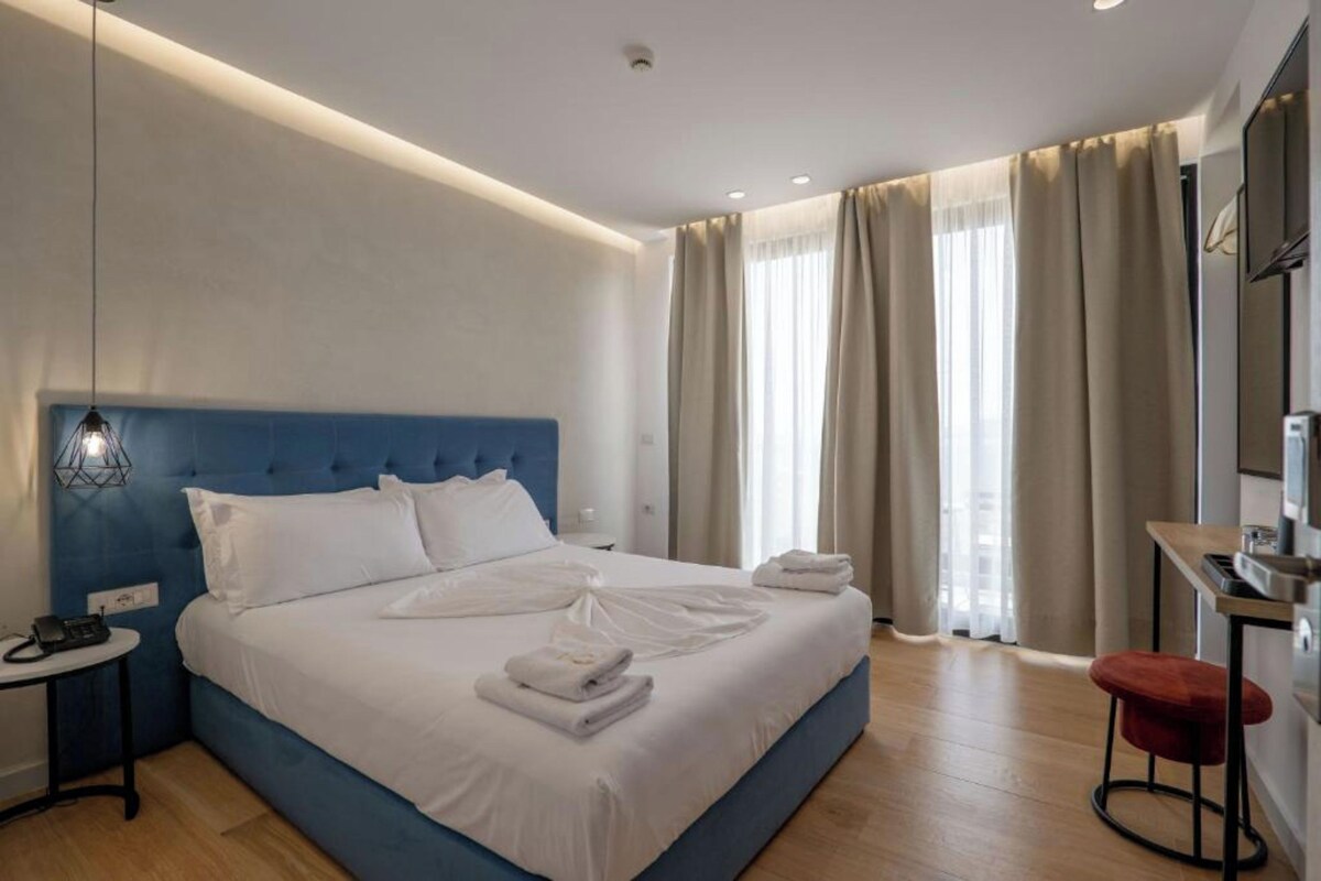 Una habitación de hotel moderna con una cama grande, un escritorio y una silla.