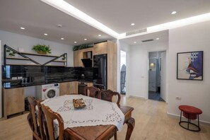 Una cocina moderna con comedor, armarios de madera, encimera negra y lavadora.