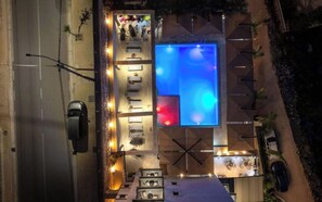 A rooftop pool with a blue-lit water feature, outdoor seating, and a view of the street below. - Art Hotel (Sarandë)