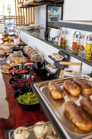 Ein reichhaltiges Buffet mit verschiedenen Speisen, darunter Früchte, Gebäck und Getränke.