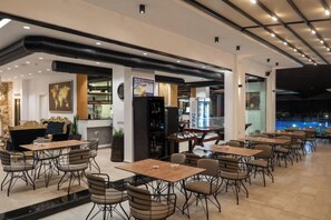 A modern restaurant with a bar area, dining tables, and chairs. - Art Hotel (Sarandë)