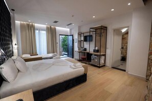 Quarto de hotel moderno com uma cama grande, uma escrivaninha, uma televisão e vista para o exterior.