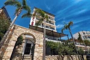 Un edificio moderno con fachada de piedra, varios balcones y palmeras.