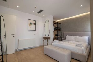 A modern bedroom with a large bed, a bedside table, a mirror, and a radiator. - Art Hotel (Sarandë)