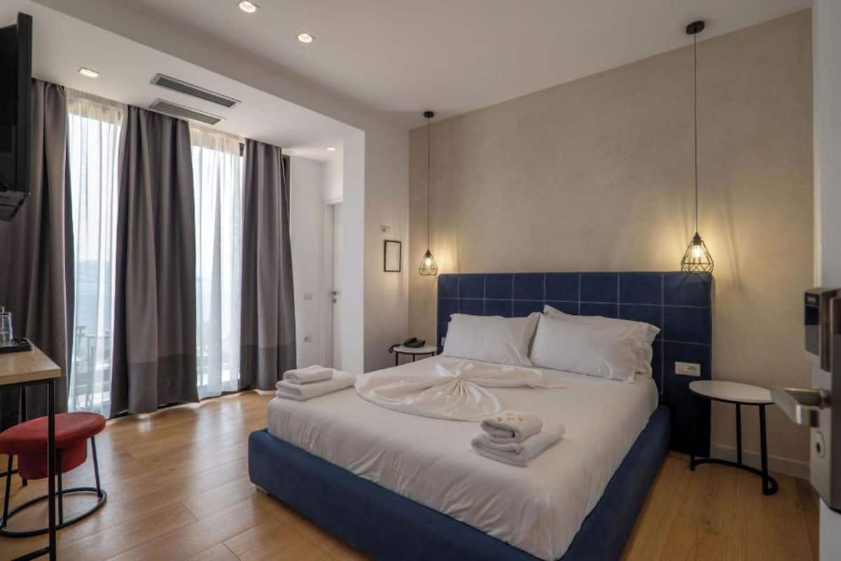 A modern hotel room with a large bed, a desk, and a chair.
