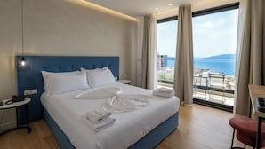 Habitació d'hotel amb un llit gran, vistes al mar i un balcó amb moble d'exterior.