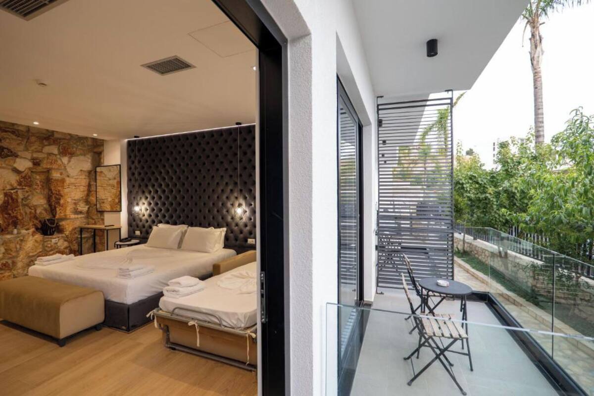 A modern bedroom with a large bed, a sofa, and a balcony with a glass railing.