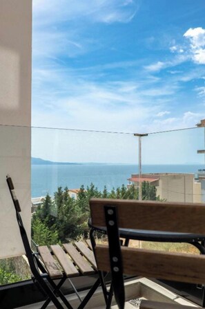 A balcony with a wooden bench, a view of the sea, and buildings in the distance. - Art Hotel (Sarandë)