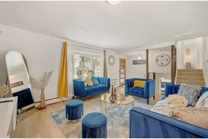A modern living room with two blue sofas, a coffee table, and a large mirror.