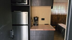 Een kleine keuken met een inbouwmagnetron, een roestvrijstalen koelkast, een koffiezetapparaat en een houten aanrecht.