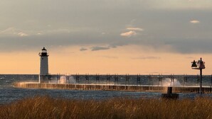 Een vuurtoren en steiger die zich uitstrekken in de zee, met golven die ertegen slaan.