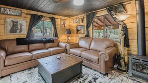 Un intérieur de chalet chaleureux avec deux canapés en cuir, une table basse en bois et un poêle à bois.
