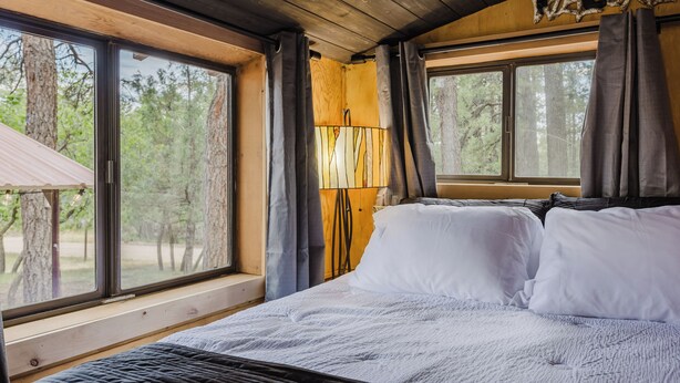 Une chambre dans une cabane en bois, avec un lit, une fenêtre et une pancarte « Bienvenue ».