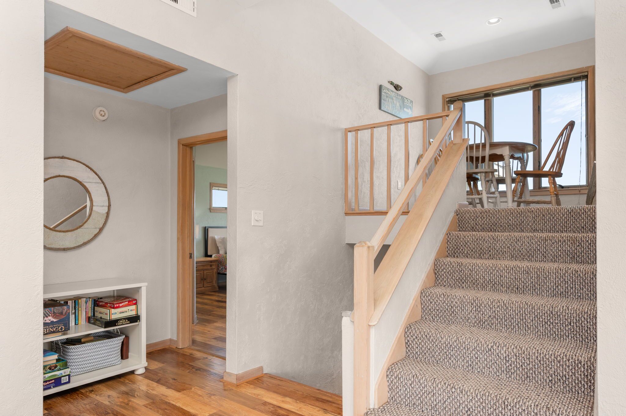 Un escalier avec des rampes en bois menant à un coin repas équipé d’une table et de chaises.