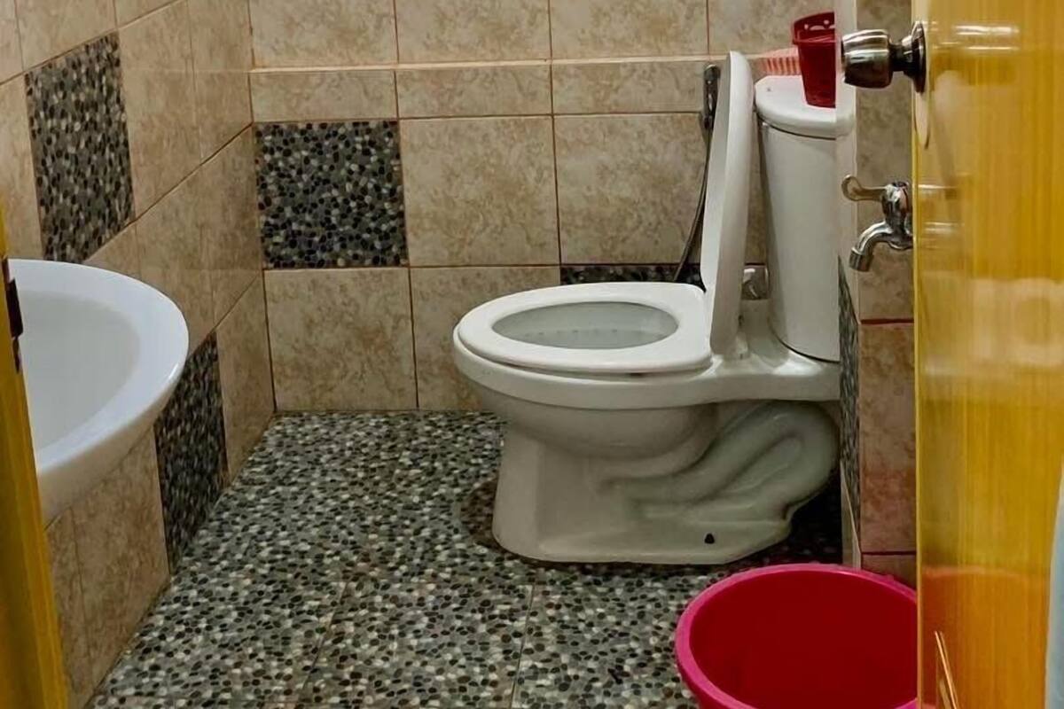 A small bathroom with a toilet, a sink, and a window.